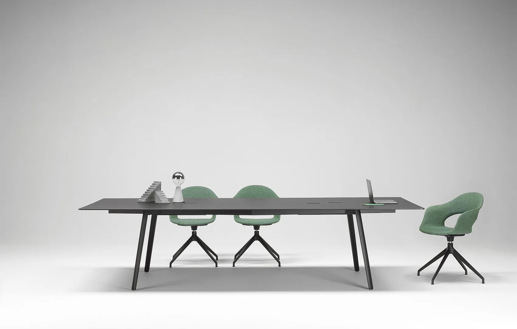 S•CAB Squid OF Office Meeting Table with a black tabletop, integrated cable management, and angled legs in a contemporary conference room with swivel chairs.