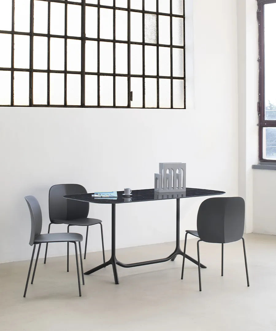 S•CAB Tripé Double Dining Table Base with a black rectangular tabletop paired with upholstered dining chairs in a contemporary indoor dining space.