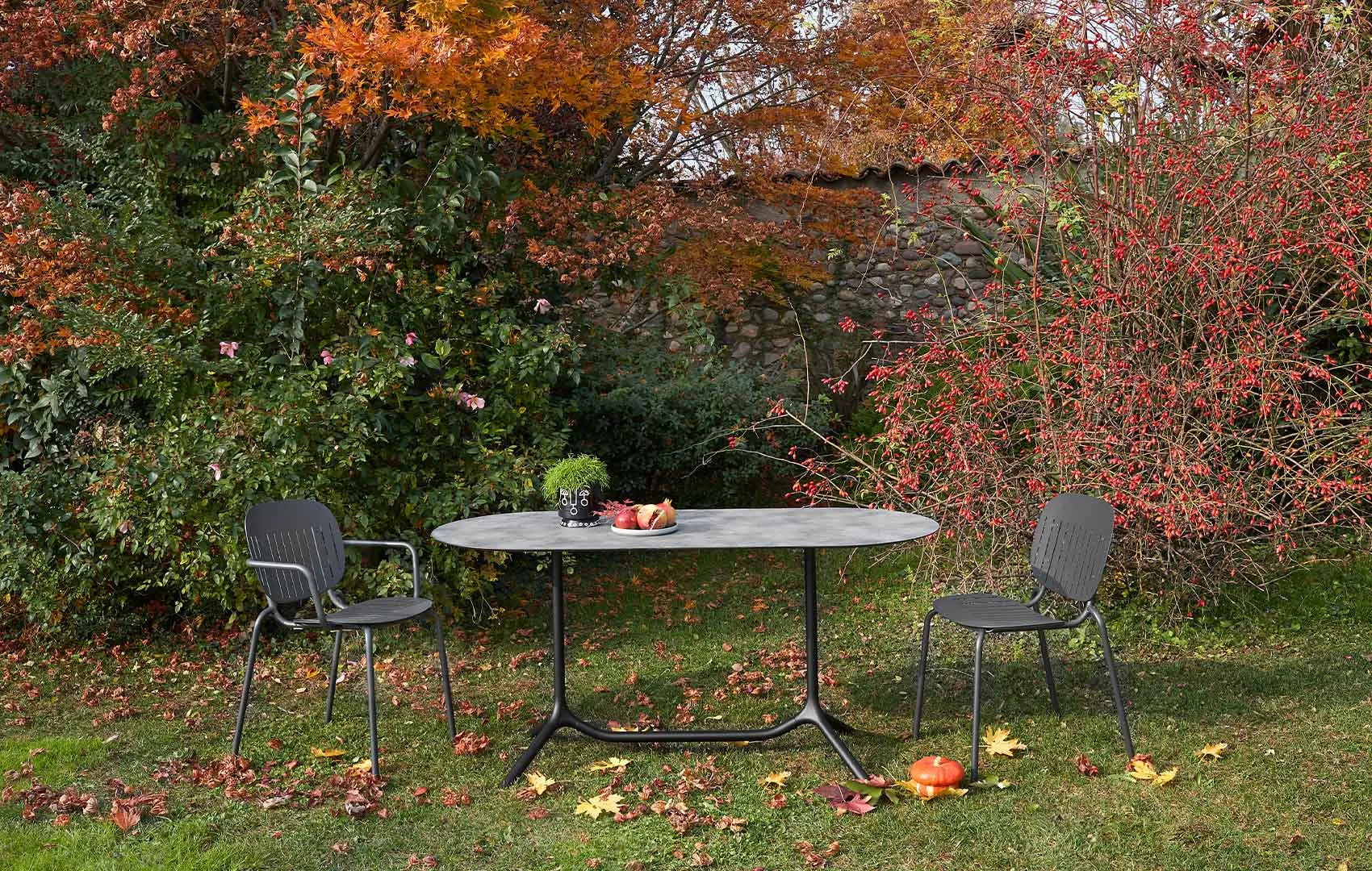S•CAB Tripé Double Dining Table Base with an oval stone-effect tabletop paired with outdoor chairs in a contemporary garden dining setting.