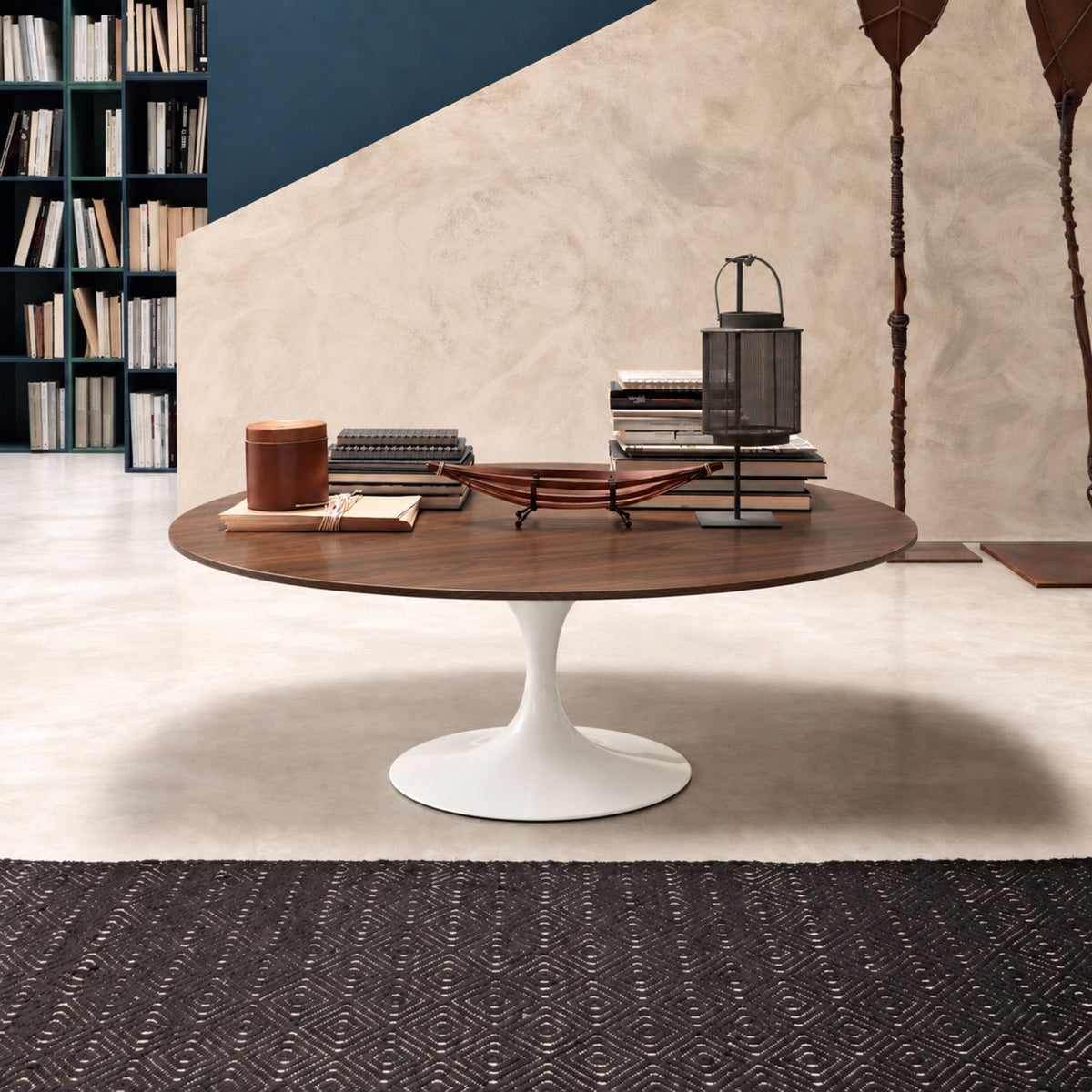American walnut veneer Tulip coffee table with a rich dark wood round tabletop and glossy white pedestal base, styled in a contemporary living room with books, decorative accessories, and modern furnishings. Luxury Italian designer coffee table for modern, Scandinavian, mid-century, and minimalist interiors.