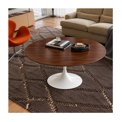 Walnut Prestige Tulip coffee table featuring a premium American walnut veneer round tabletop paired with a glossy white tulip pedestal base. Styled in a contemporary living room with a beige sofa, orange accent chair, textured rug, books, coffee cup, and decorative tray, showcasing timeless Italian design for modern, Scandinavian, mid-century, and minimalist interiors.