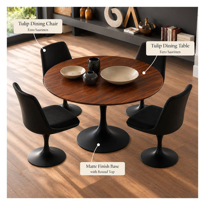 Round walnut Eero Saarinen Tulip dining table with a matte black pedestal base paired with four black upholstered Tulip dining chairs in a contemporary dining room.