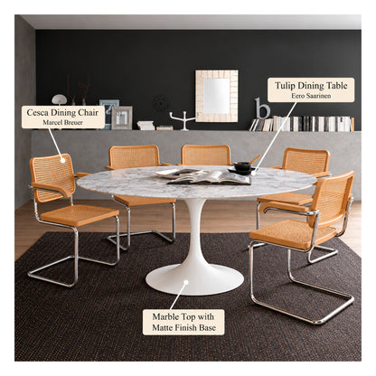 White marble round Eero Saarinen Tulip dining table with a white pedestal base paired with four Cesca armchairs featuring natural cane seats and backs, chrome cantilever frames, and wooden armrests in a contemporary dining room.