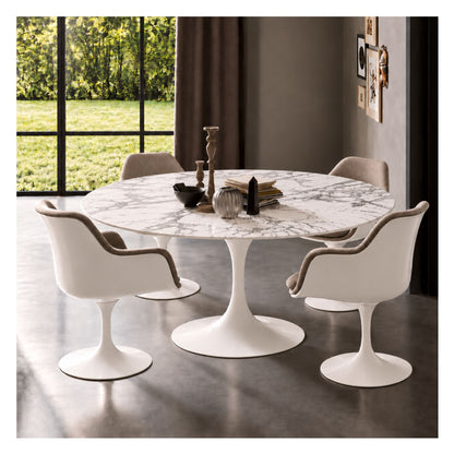 White marble round Eero Saarinen Tulip dining table with a white pedestal base paired with four white Tulip armchairs featuring light grey upholstered cushions in a contemporary dining room.
