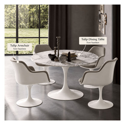 White marble round Eero Saarinen Tulip dining table with a white pedestal base paired with four white Tulip armchairs featuring light grey upholstered cushions in a contemporary dining room.