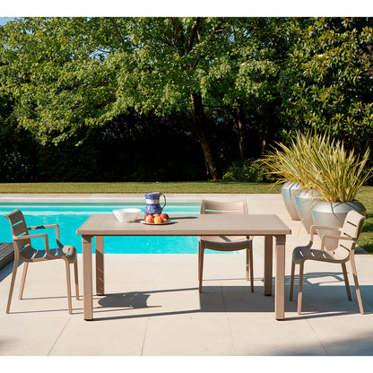 SCAB Sunset outdoor armchairs paired with a matching dining table beside a swimming pool, creating a modern Italian garden dining space for patios, terraces and hospitality settings.